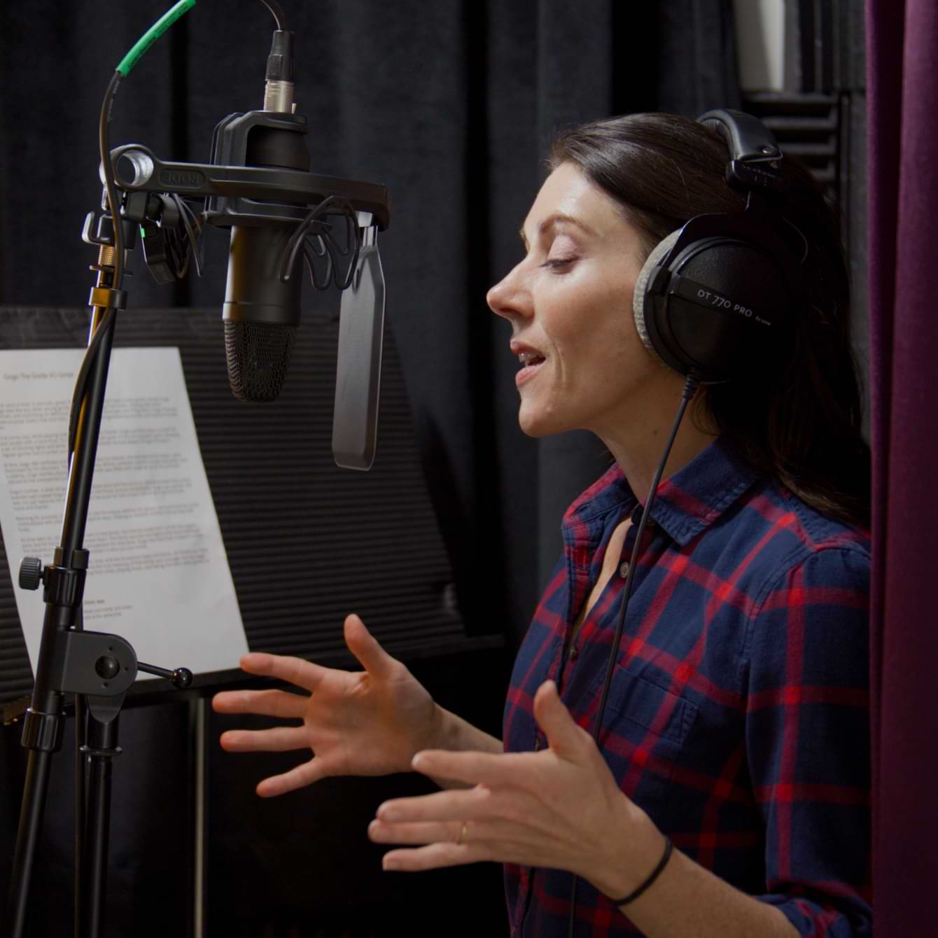 A voiceover artist and QuickBooks Live customer is standing in front of a microphone in a recording studio. 