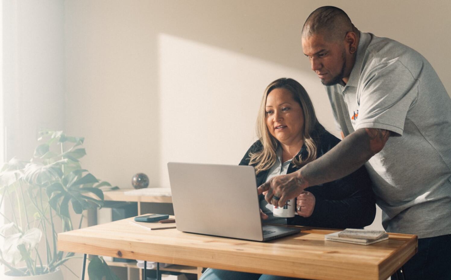 Man and woman working together at the laptop in the office. Man is pointing at the screen.