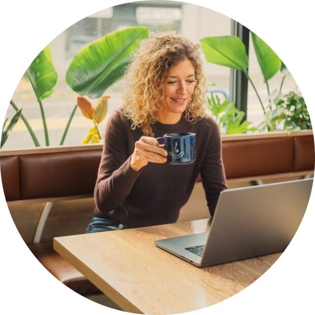 Woman drinking coffee and working on her laptop.