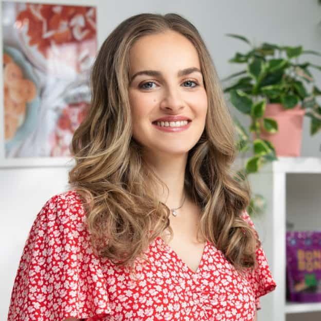 A person smiles as she sits in a kitchen.